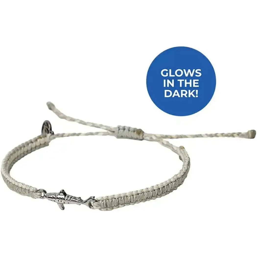 A close-up of the 4Ocean Respect the Locals Tiger Shark Bracelet with a blue "GLOWS IN THE DARK!" circle above it.