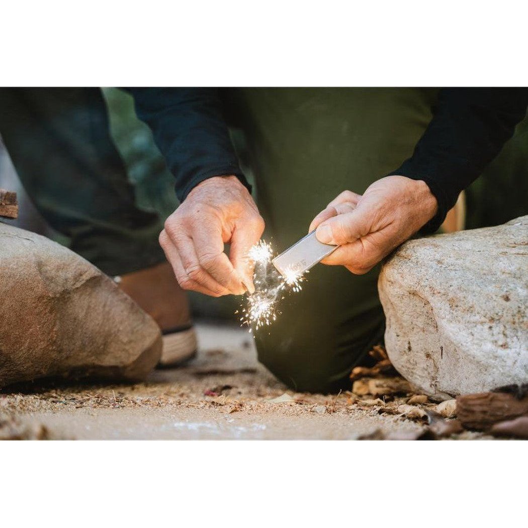 A person outdoors uses the Adventure Medical Kits Mag Block to create sparks between two rocks.