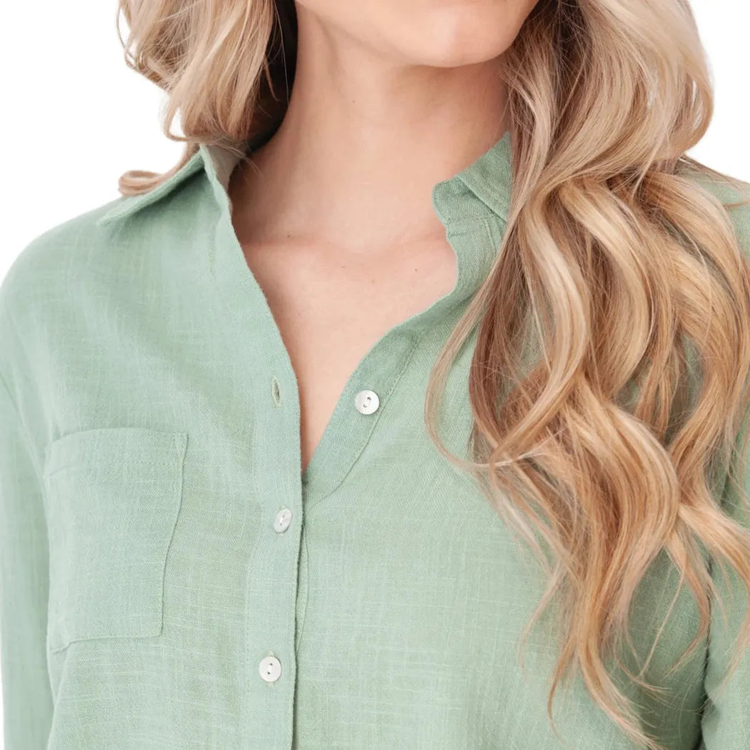 A close-up of the Aventura Women's Laken Top in Granite Green, showing the collar and front pocket on a model with wavy hair.