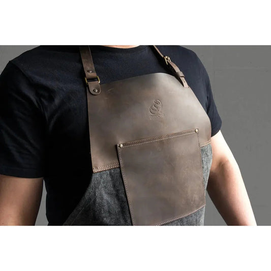 A front view of the Beavercraft Cowhide Apron Leather with a leather pocket and adjustable straps on a model wearing a black shirt.