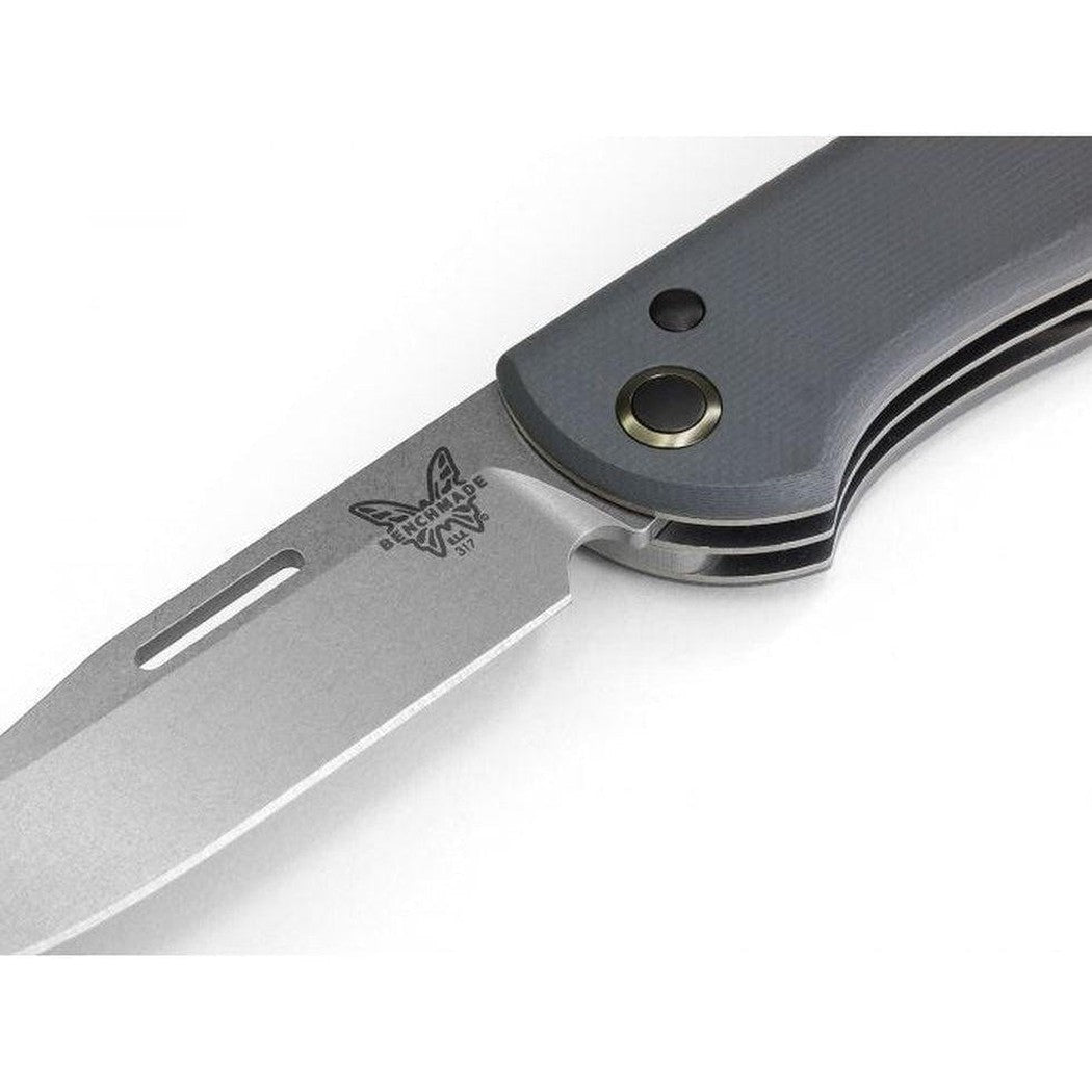 A close-up side view of the Benchmade Weekender knife with a charcoal/gray handle and a silver blade, showing the logo and a lanyard hole against a white background.