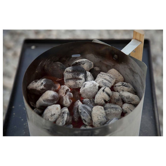 A Camp Chef Charcoal Lighter Basket filled with charcoal sits on a black tray outdoors.