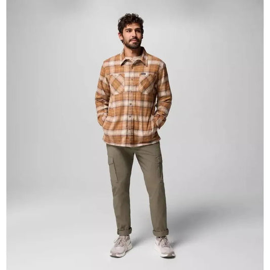 A model wearing the Columbia Sportswear Men's Cornell Woods Fleece Lined Shirt Jacket in Delta Lumberjack Tartan stands against a light gray background.