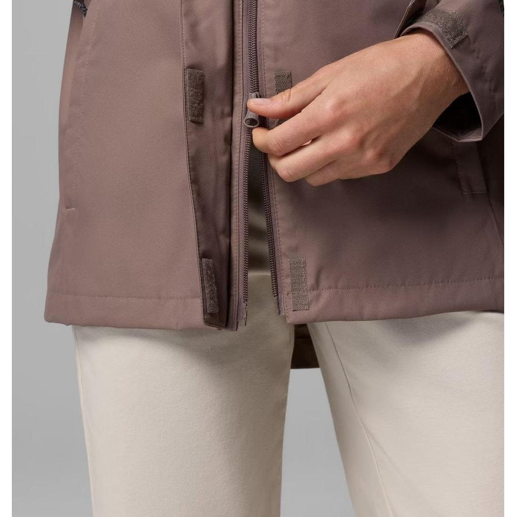 A woman’s hand zips the front of the Columbia Sportswear Women’s Hikebound II Long Jacket in Iron, showing the zipper pull and fabric texture.