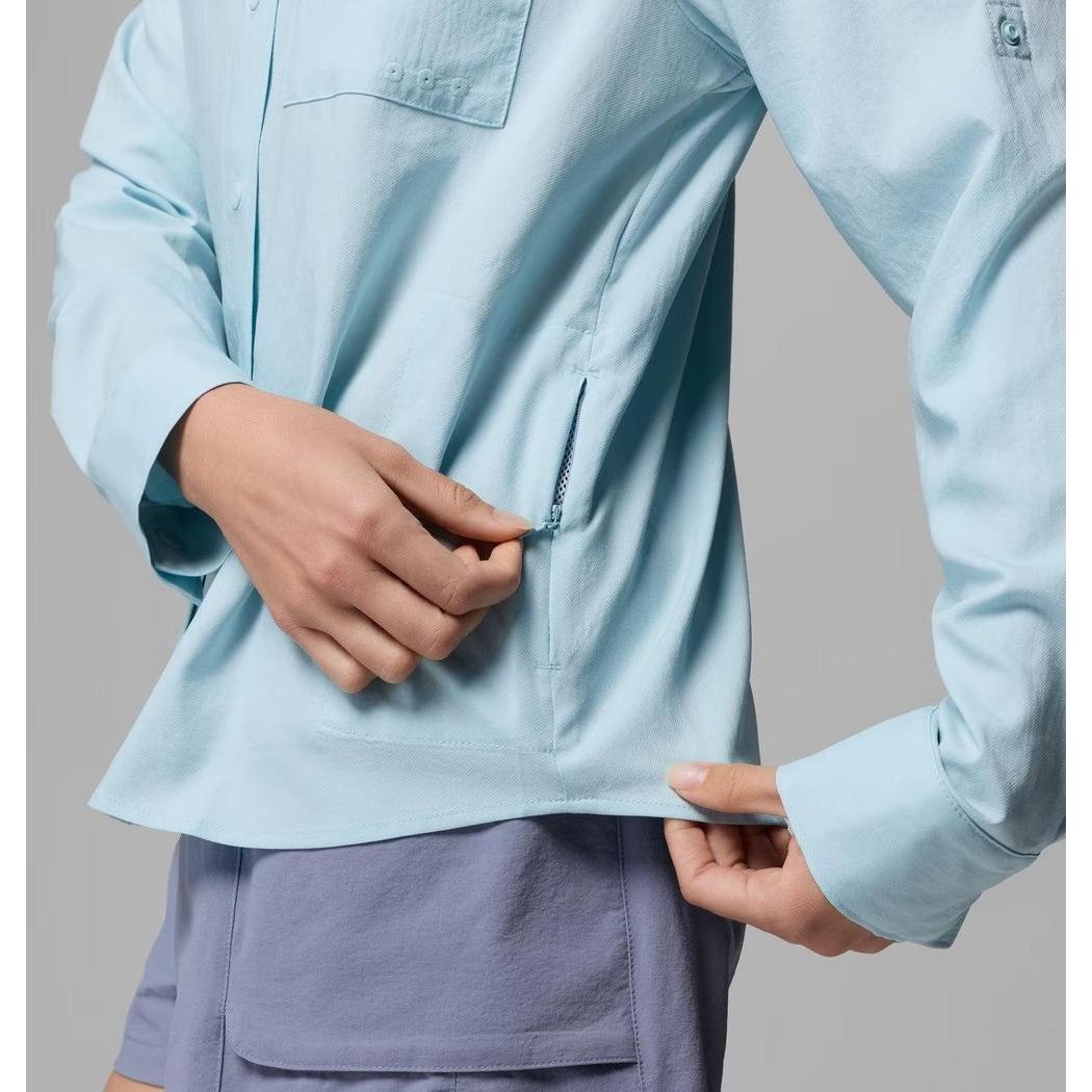 A woman models the Columbia Sportswear Women's PFG Castback Woven Long Sleeve in Marine Light, showing the side zipper and pocket.