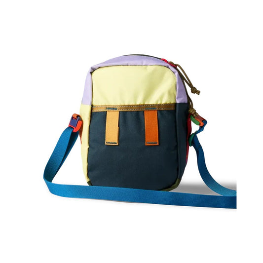 Side view of the Cotopaxi Todo 1L Shoulder Bag - Del Dia showing the blue shoulder strap and colorful front pockets against a white background.