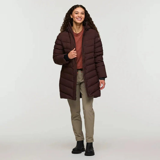 A model wearing the Cotopaxi Women's Alivio Down Parka in Coffee stands against a plain white background.