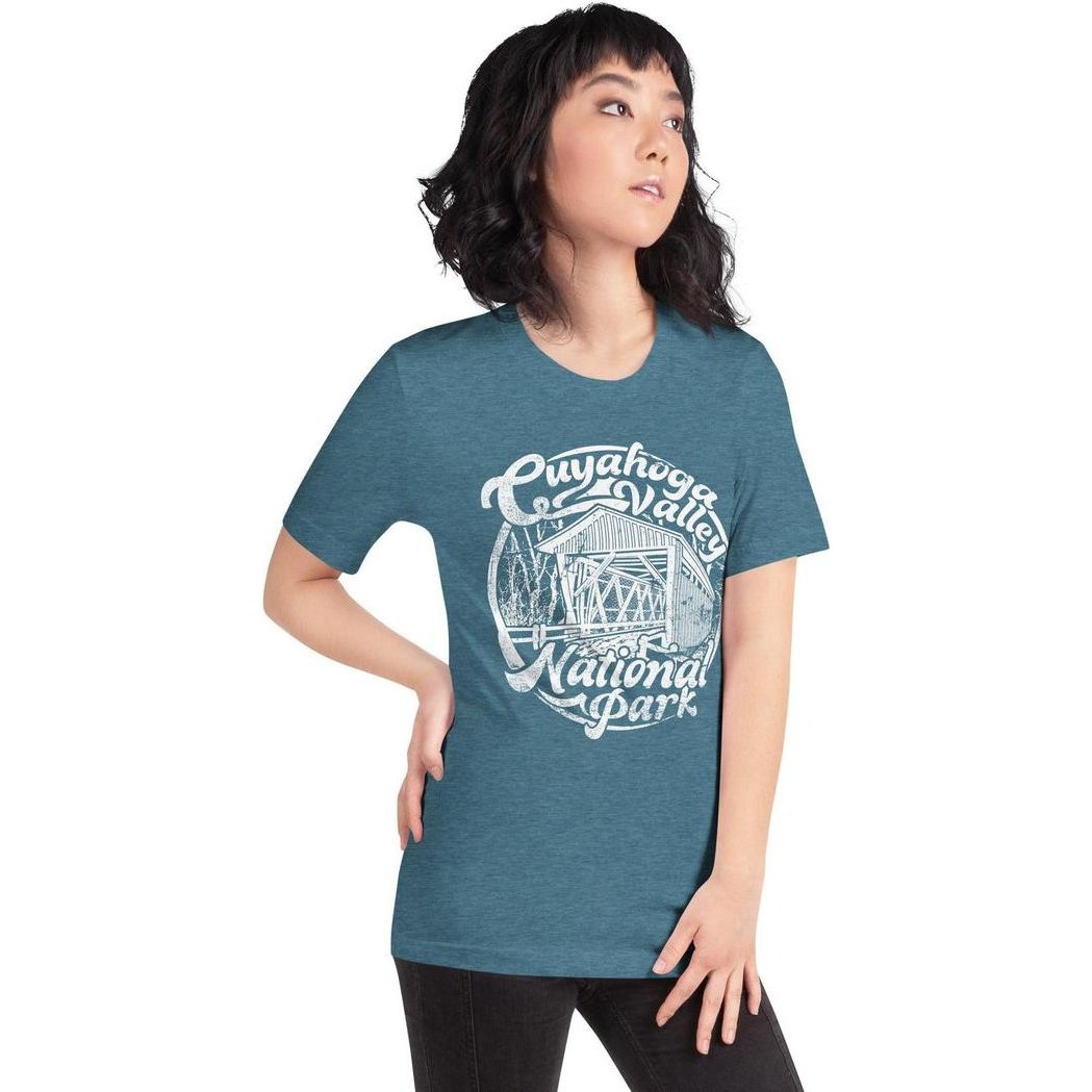 A woman models the Heather Deep Teal Cuyahoga Valley Clothing Company CVNP Covered Bridge T - Shirt from the side against a white background.