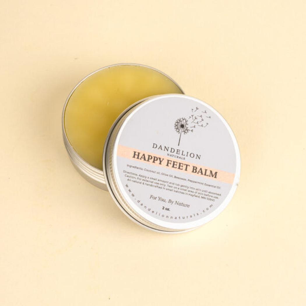 A round tin of Dandelion Naturals Happy Feet Balm sits open on a light background.