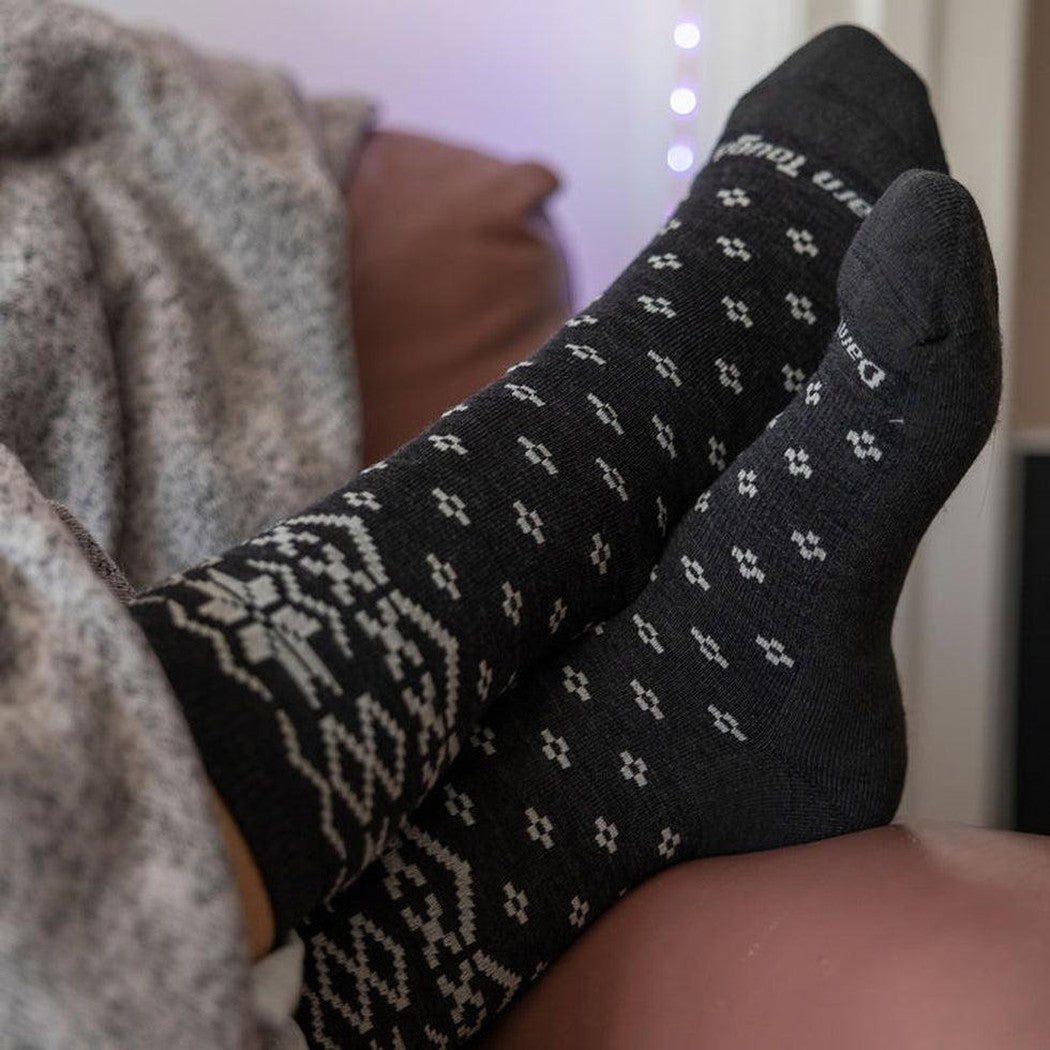 A close-up of Darn Tough Women's Shetland Crew Lightweight with Cushion socks in Burgundy, showing the pattern and cushioned sole on a woman's feet with a cozy blanket in the background.