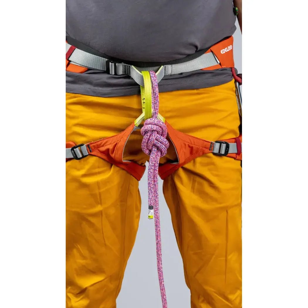 A front view of the Edelrid Jay IV women's climbing harness in Hokkaido color, showing the waist belt and leg loops on a model wearing yellow pants.