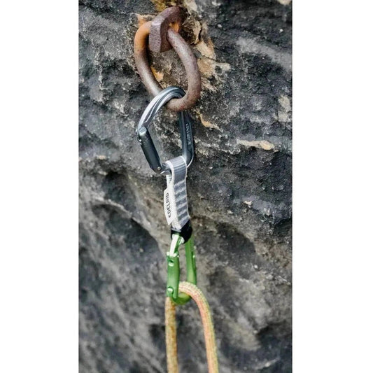 A close-up of the Edelrid Pure Set Sixpack, 10cm, quickdraws with a green carabiner and rope against a rocky background.