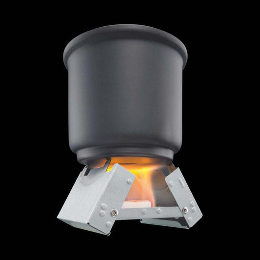 A close-up of the Esbit Pocket Stove with a charcoal/ graphite pot on top, showing the flame and metal base against a black background.