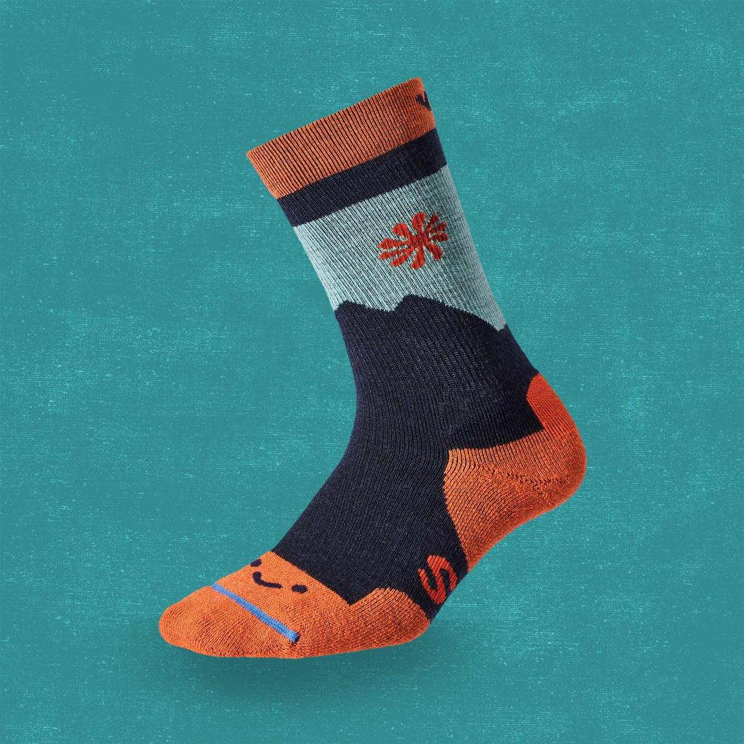 Side view of the FITS Light Cushion Crew Navy socks showing the mountain graphic and orange toe against a teal background.