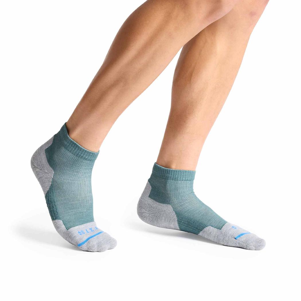 A side view of the FITS Light Hiker Quarter socks in Coal color on a model's feet against a white background.