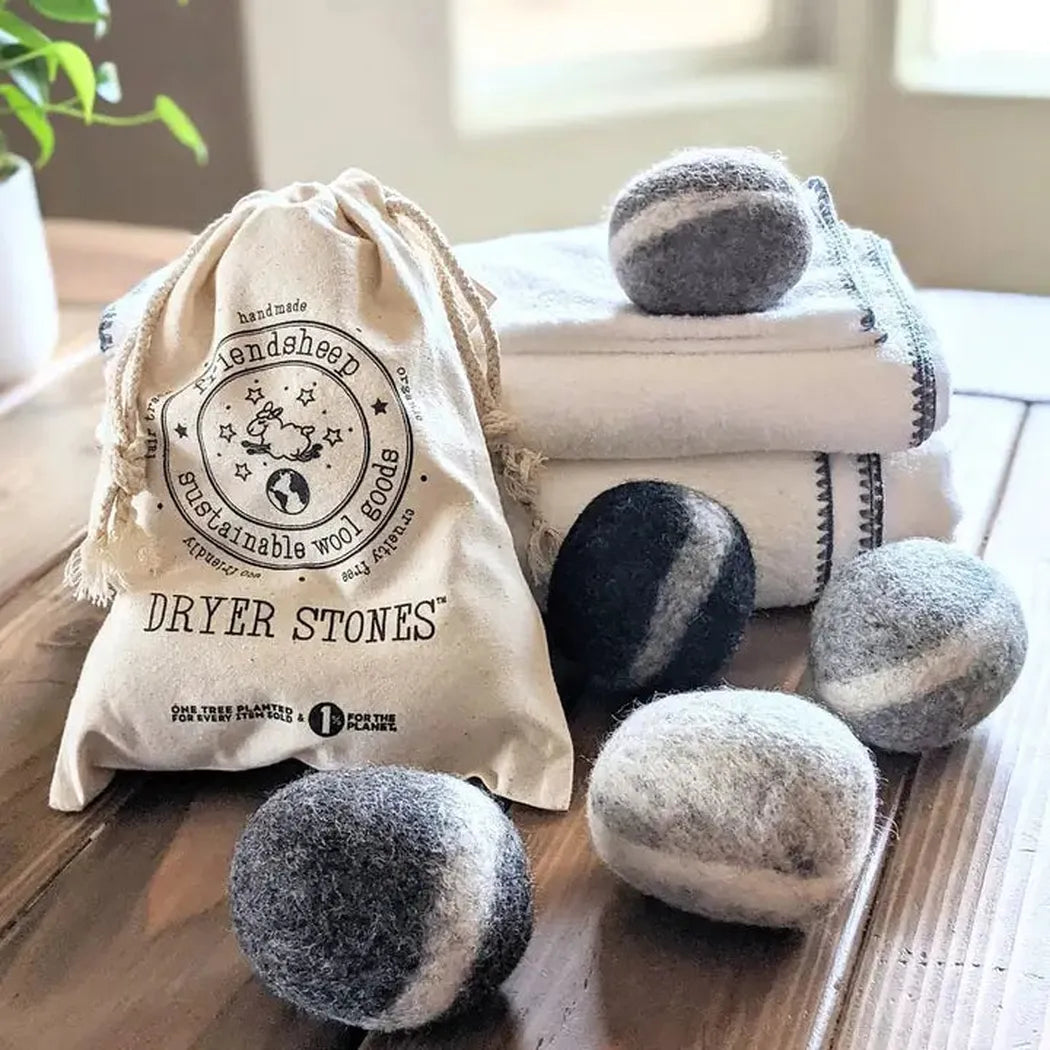 A top-down shot of handmade Friendsheep Dryer Stones Eco Wool Dryer Balls on a wooden table with folded towels in the background.