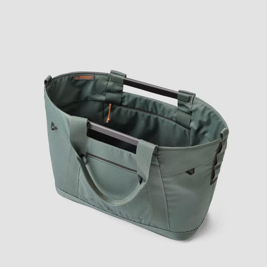 Side view of the Gregory Alpaca Utility Tote 35L in Nomad Green showing the top handles and front pocket against a light gray background.