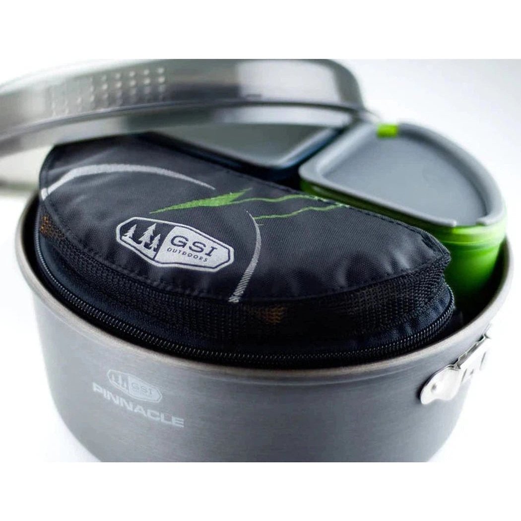 A top-down view of the GSI Outdoors Crossover Kitchen Kit in Charcoal/Graphite showing the GSI logo on the pouch and a green container inside the pot.