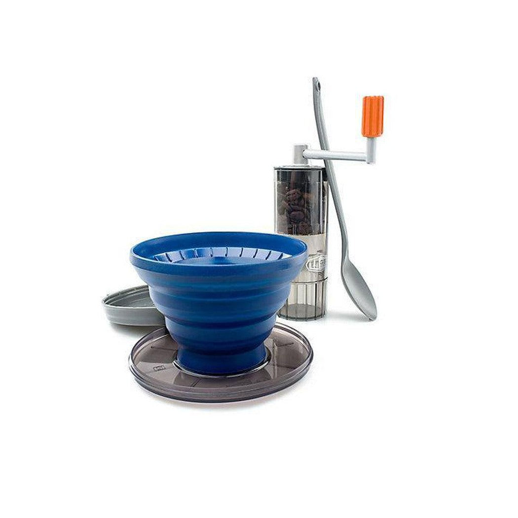 A blue GSI Outdoors Gourmet Pourover Java Set sits on a charcoal base with a coffee grinder and spoon in the background.