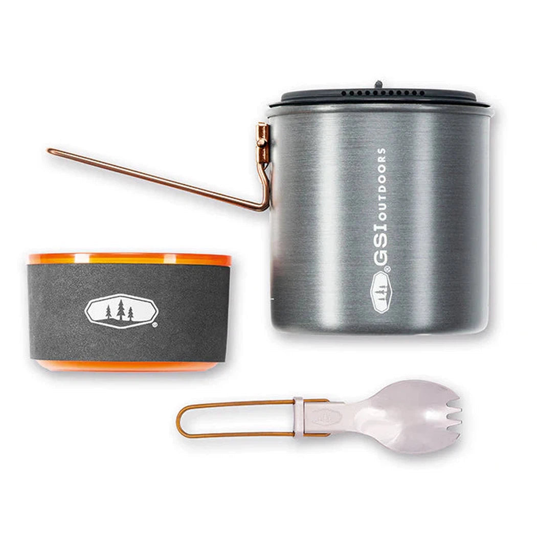 A top-down view of the GSI Outdoors Halulite Soloist camping cook set with a charcoal pot, orange-rimmed bowl, and white utensil against a white background.