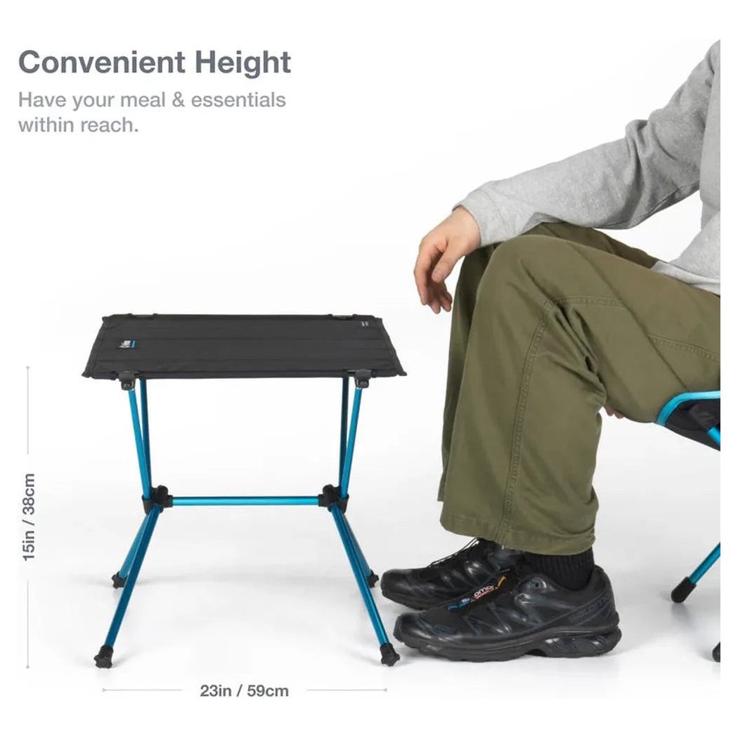 A side view of the Helinox Table One Hard Top in Black R1 showing its convenient height next to a seated model.