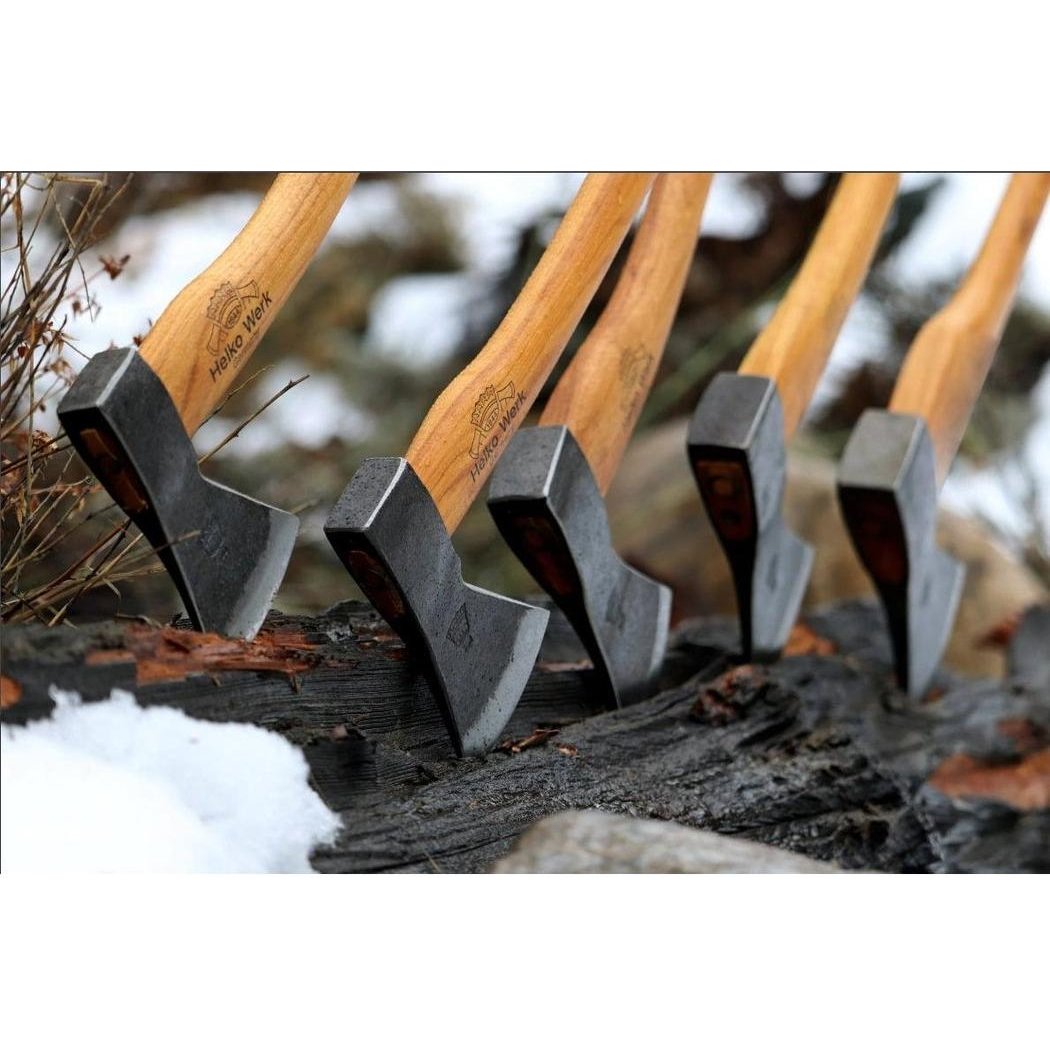 Five Helko Werk Bavarian Woodworker axes with wooden handles stand upright on a log with snow in the background.