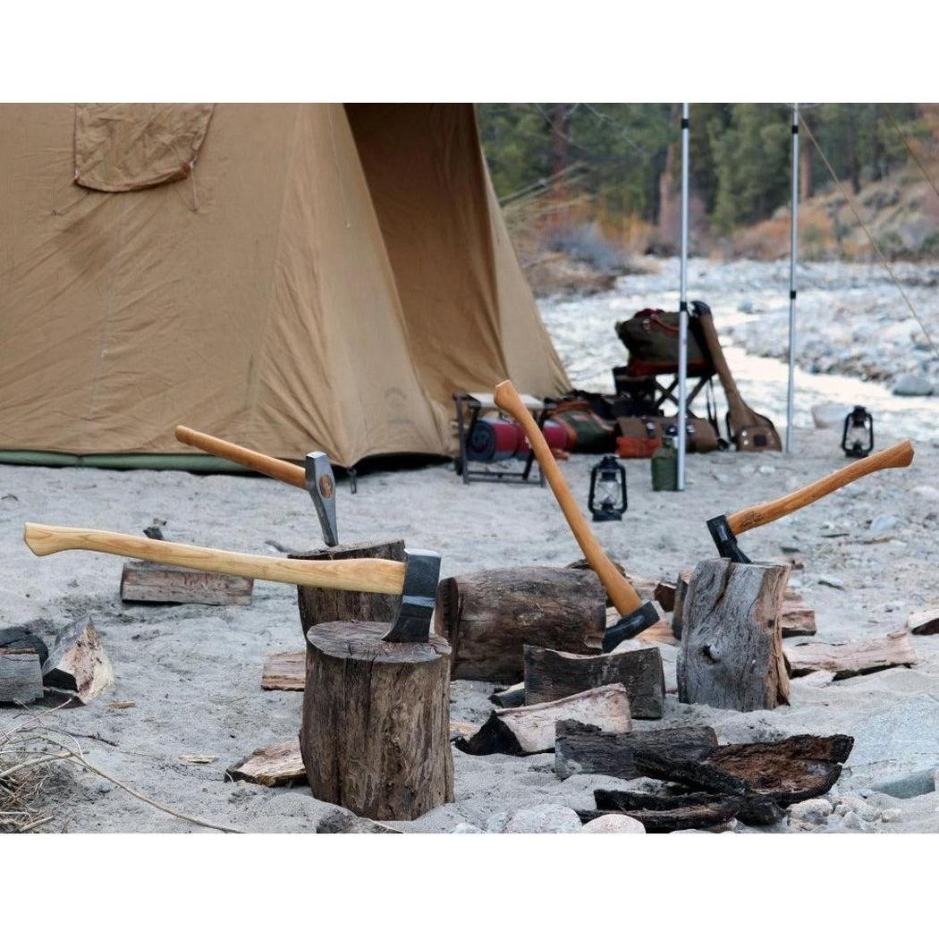 A tan tent and camping gear sit behind three Helko Werk Heidelberg Mini Splatters on tree stumps in a rocky campsite.