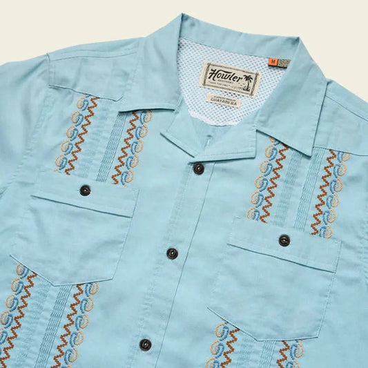 A close-up of the Howler Brothers Men's Guayabera Shirt in Nile Blue showing the embroidered details and button front against a light background.