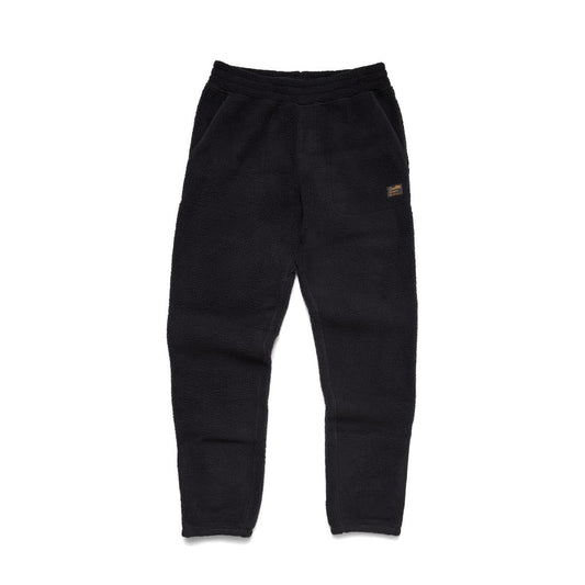 Side view of the Howler Brothers Men's Pelusa Fleece Pants in Pine Needle showing the small patch on the right thigh against a white background.