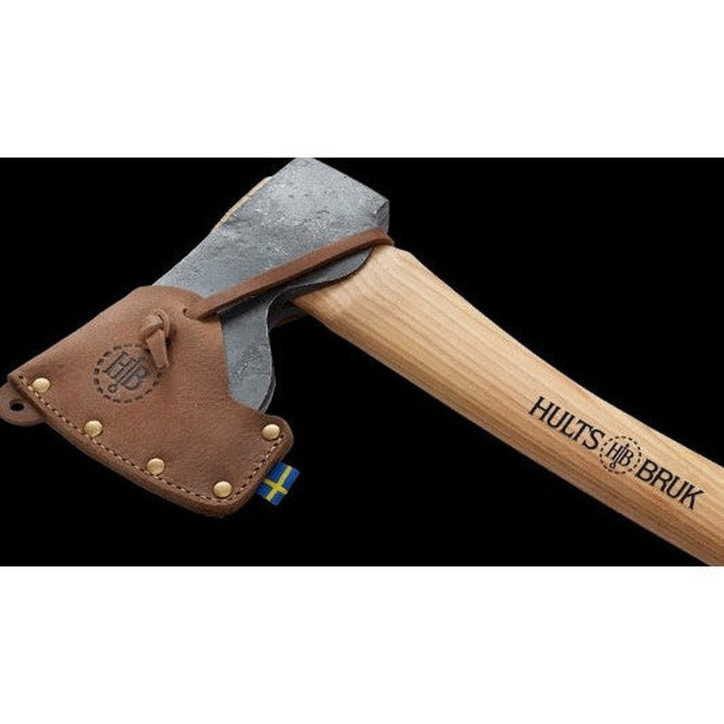 A side view of the Hults Bruk Spika Hunting and Forest Axe with a natural wood handle and brown leather sheath against a black background.