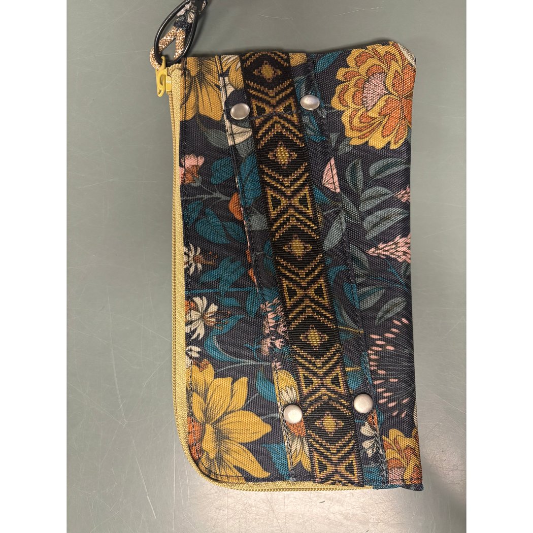 A top-down view of the Kavu Clutch Case in Frosty Foliage showing the zipper and decorative strap against a gray background.
