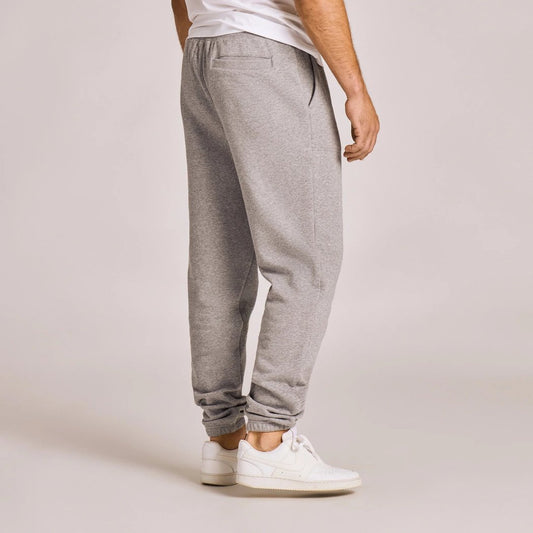 Side view of the Life is Good Men's Solid Good Vibes Jogger in Heather Gray showing the elastic cuffs and white sneakers against a light background.