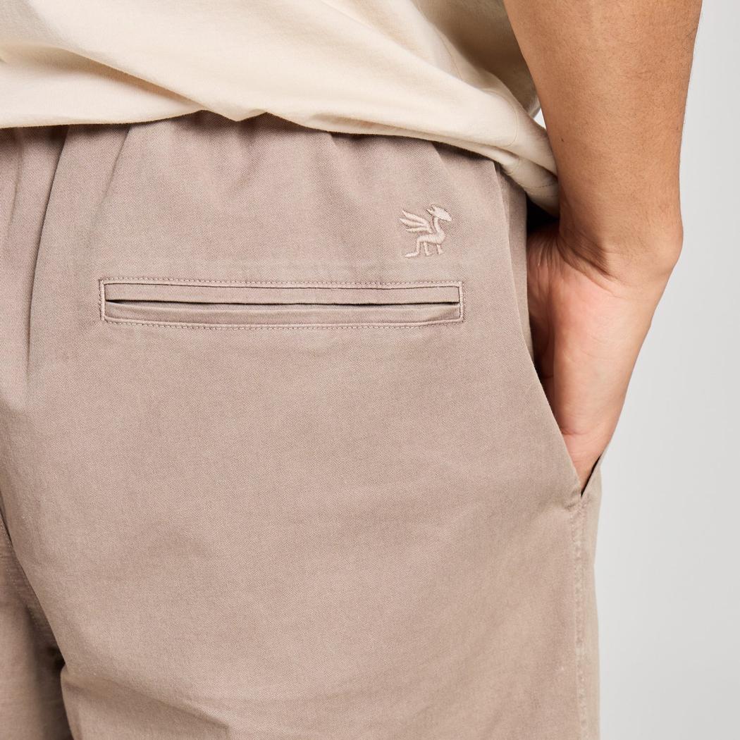 Back view of the Life is Good Men's Solid Weekender Short in Mushroom Brown showing the back pocket and model's hand in pocket.