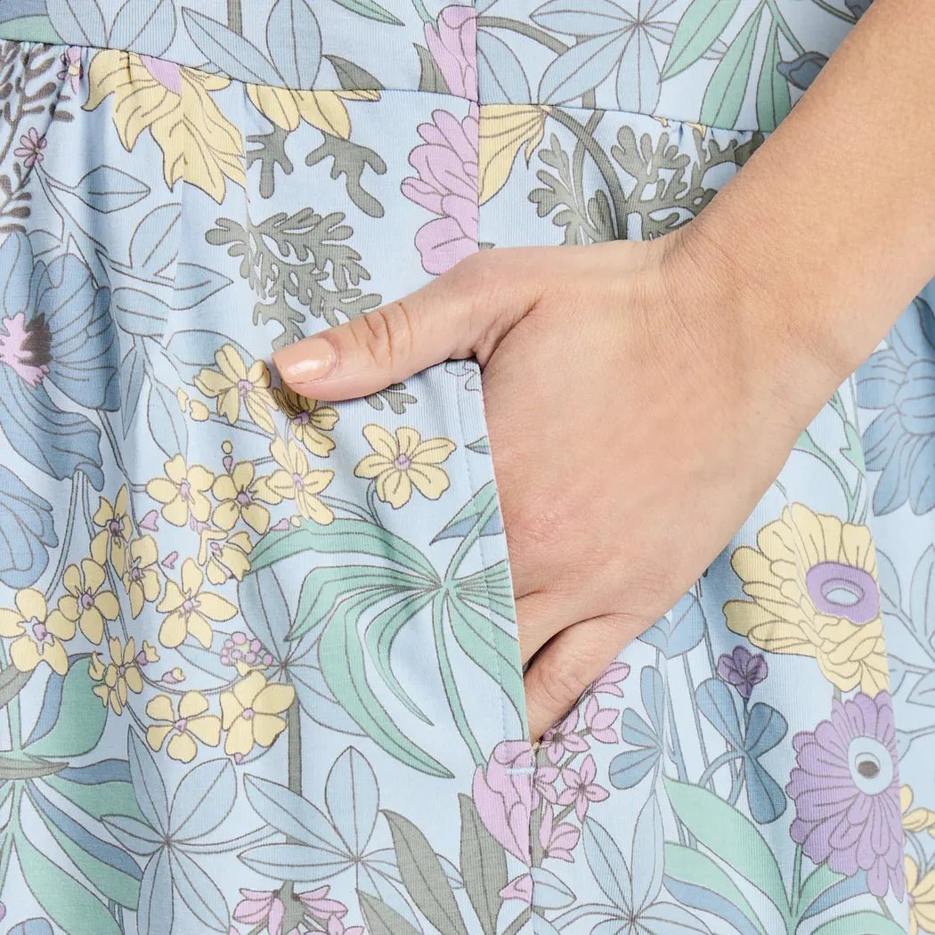 A hand in a pocket of the Life is Good Women's Botanical Garden Pattern Tiered Tank Dress in Glacier Blue shows the floral print.