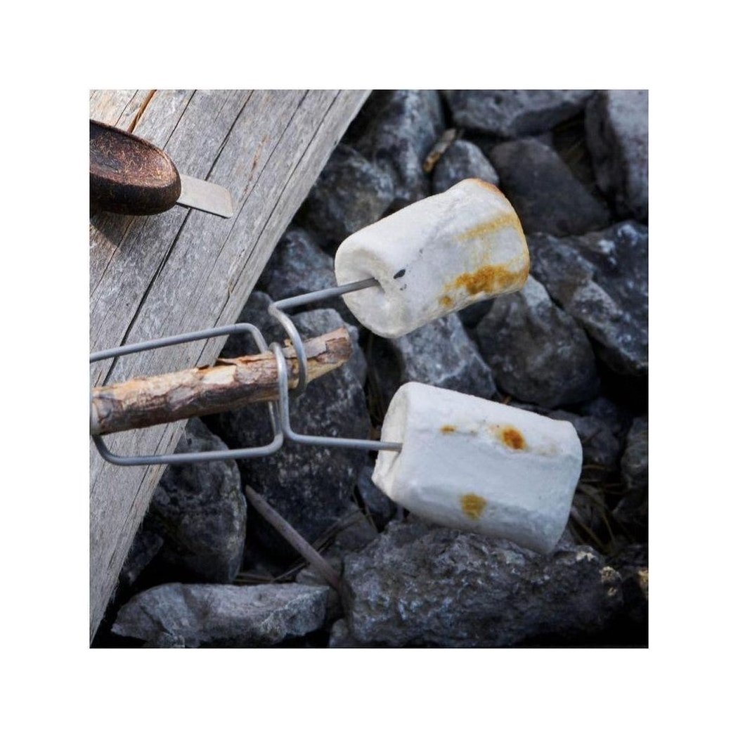 A Light My Fire GrandPa's FireFork BIO 2-pack with two marshmallows roasting over a stick, set against a rocky background and wooden surface.