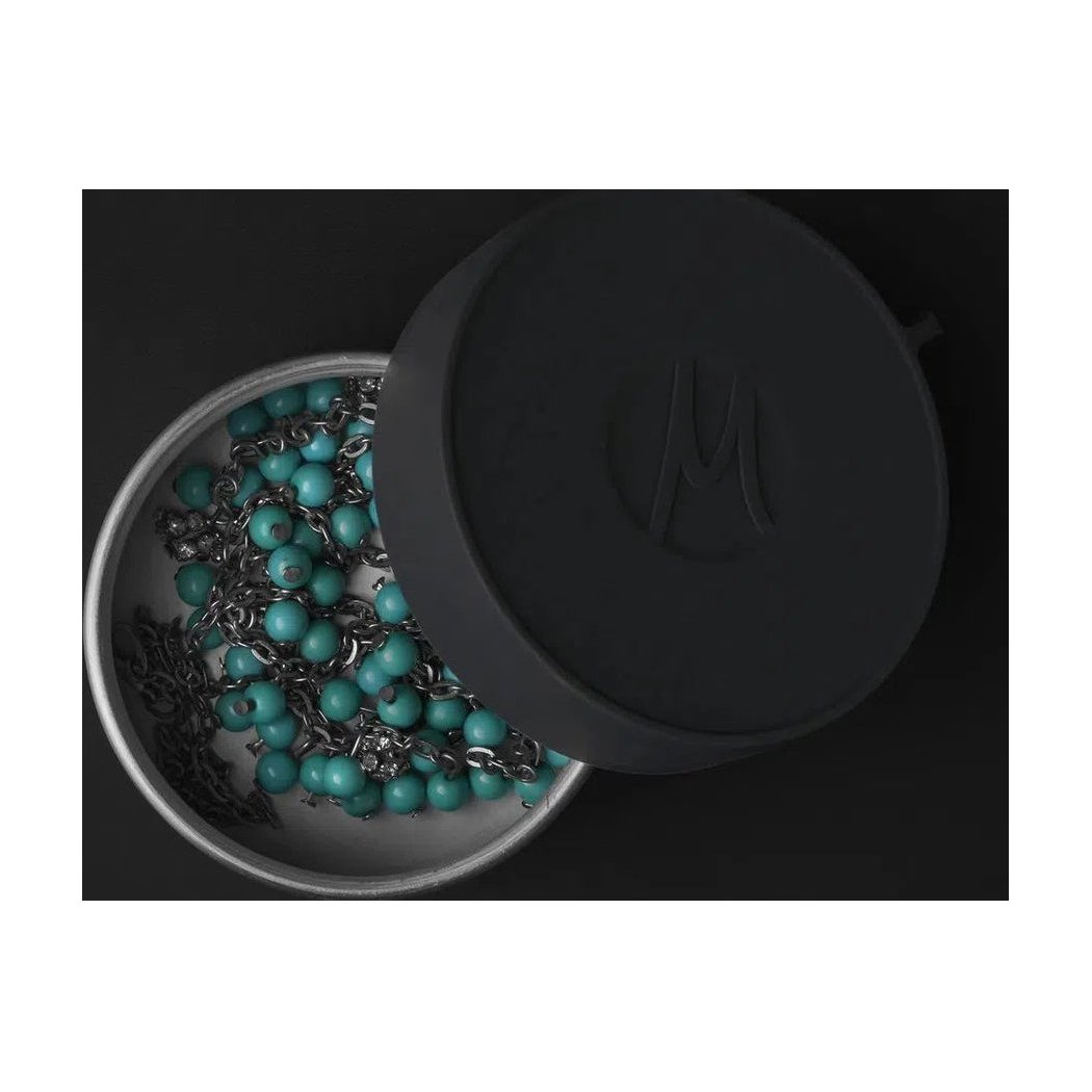 A top-down view of the Matador Waterproof Travel Canister - 100ml with its lid open, revealing turquoise beads inside against a dark background.