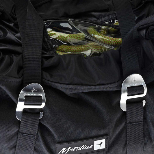 A close-up of the Metolius Rope Master HC rope bag in Rust showing the metal buckles and a green rope inside.