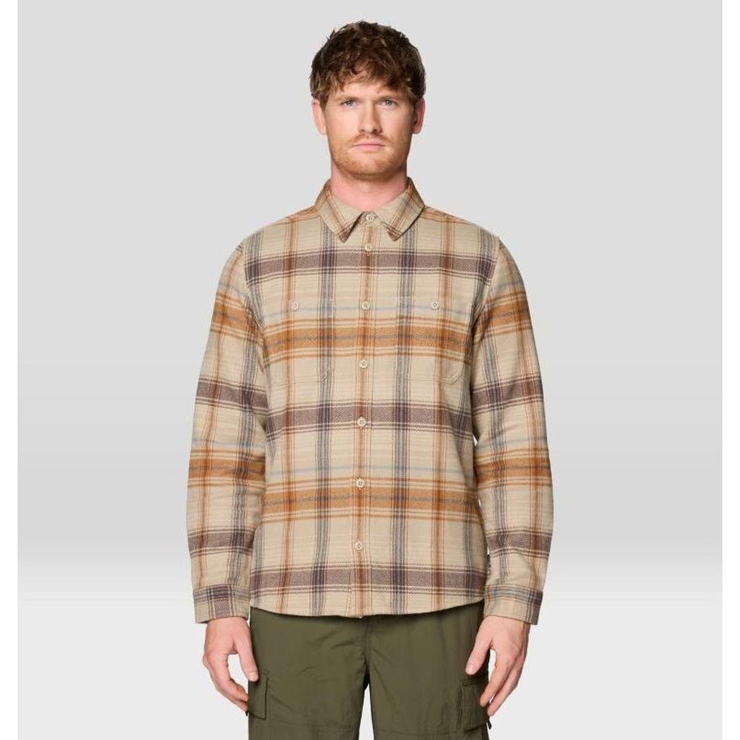 A front view of the Mountain Hardwear Men's Plusher Long Sleeve Flannel in Badlands Wyoming Plaid on a model wearing olive cargo pants against a light gray background.