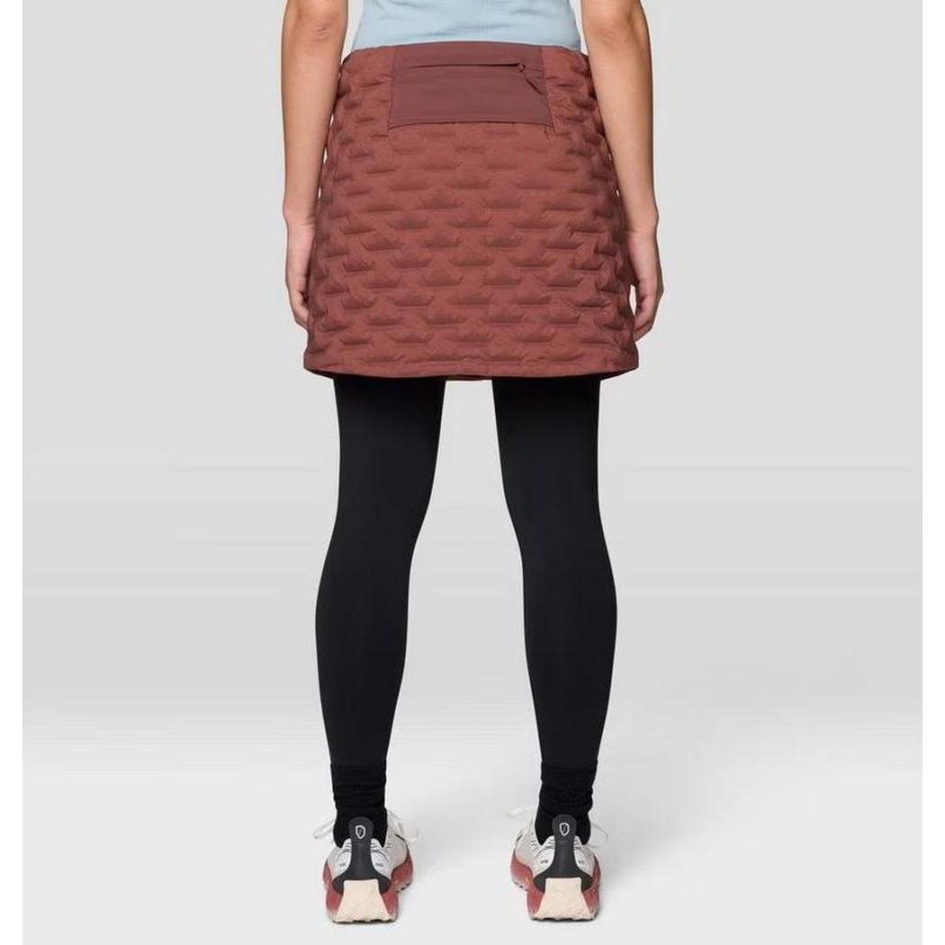 Back view of the Mountain Hardwear Women's Stretch Down Skirt in Black on a model wearing black leggings and sneakers against a plain background.