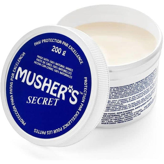 A close-up of a blue and white Musher's Secret paw protection container showing the lid and the product inside.