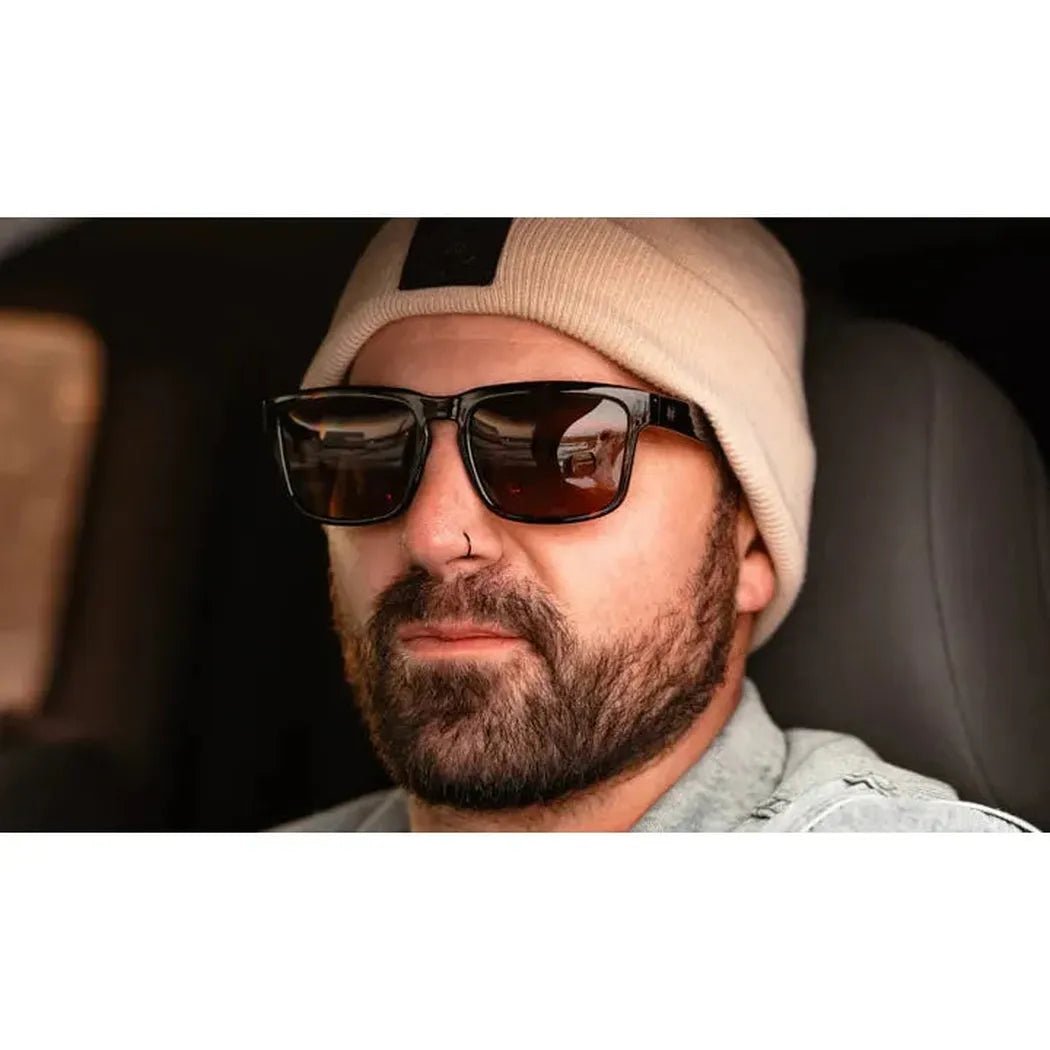 A man wearing the Optic Nerve Mashup XL black sunglasses sits in a car.