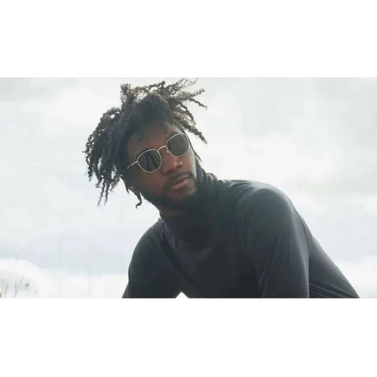 A model wearing the Optic Nerve Townsend sunglasses in a low-angle shot against a cloudy sky.