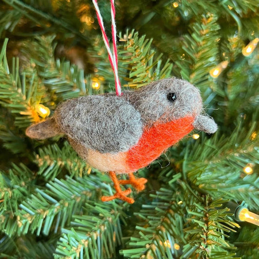 A close-up of the Ornaments 4 Orphans Bird Tufted Wool Christmas Ornament hanging on a Christmas tree with lights.