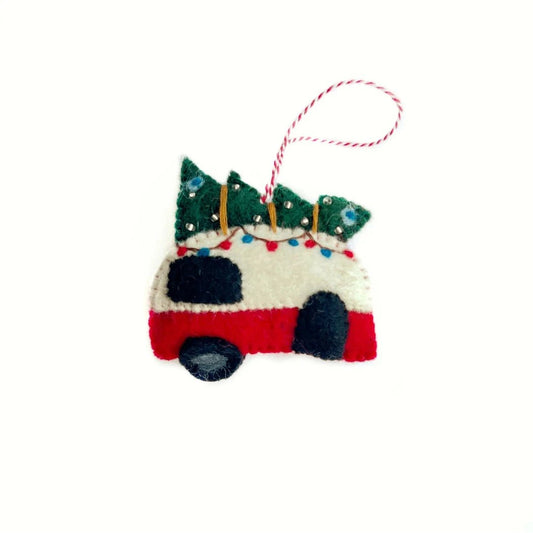 A felt Christmas ornament shaped like a red and white camper with a green tree on top, hanging from a red and white string.