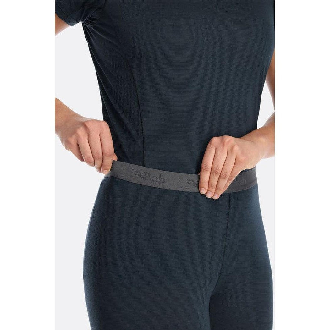 A model wearing the Rab Women's Syncrino Leggings in Beluga adjusts the waistband against a plain white background.