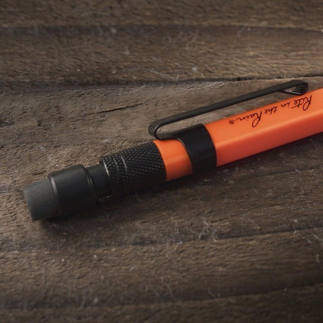 A black Rite in the Rain 1.3mm Mechanical Clicker Pencil lies on a wooden surface.