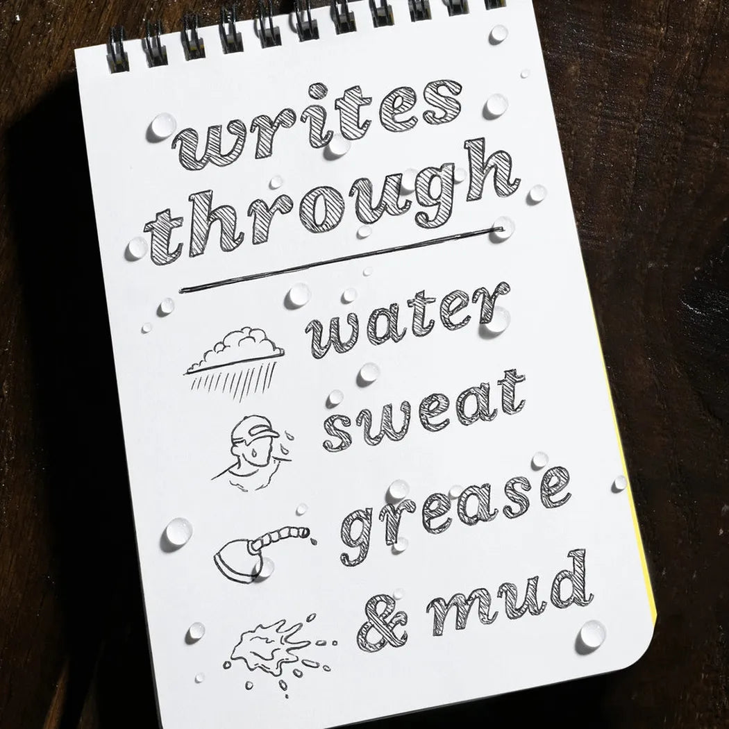 A spiral notebook with "writes through water sweat grease & mud" text and water droplets sits on a dark surface.