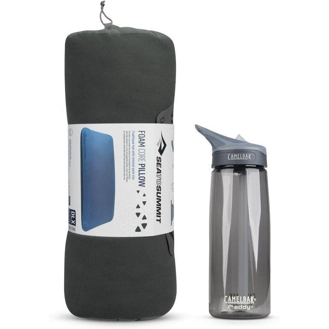 A side view of the Sea To Summit FoamCore Pillow in Grey next to a CamelBak water bottle against a white background.