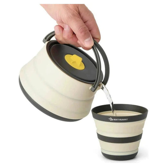 A hand pours from a Sea To Summit Frontier UL Collapsible Kettle into a matching collapsible cup against a white background.