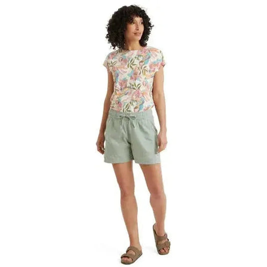 A front view of the Sherpa Adventure Gear Women's Palmo Short in Celery on a model wearing brown sandals against a white background.